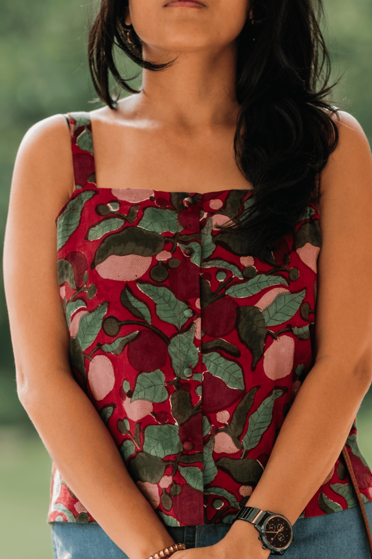 Person wearing a red floral patterned top with a blurred background